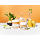 Two white cosmetic jars labeled Radeq Lab 'SUGAR PASTE 03' on a white surface against an orange background, styled with food props including a turnip, corn, and glassware.