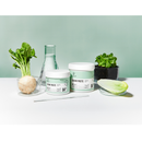Two white plastic jars of Radeq Lab sugar paste with mint green labels are displayed on a white surface with various vegetable props (turnip, lettuce, fennel bulb) and a glass bottle against a mint green background.